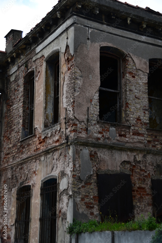 Fototapeta premium Old architecture. Abandoned brick house with peeling plaster. The windows of the house without glass.