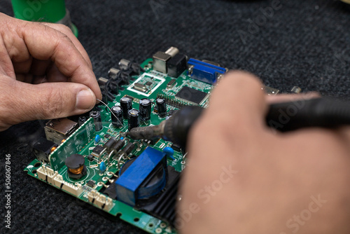 Electronic circuit board being repaired with soldering iron and tin. Repair concept, electronic