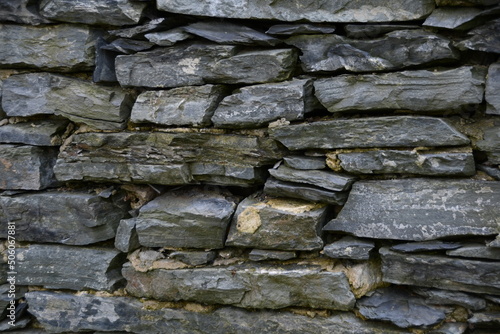 Fragment of an old stone wall. Large flat stones in the wall.