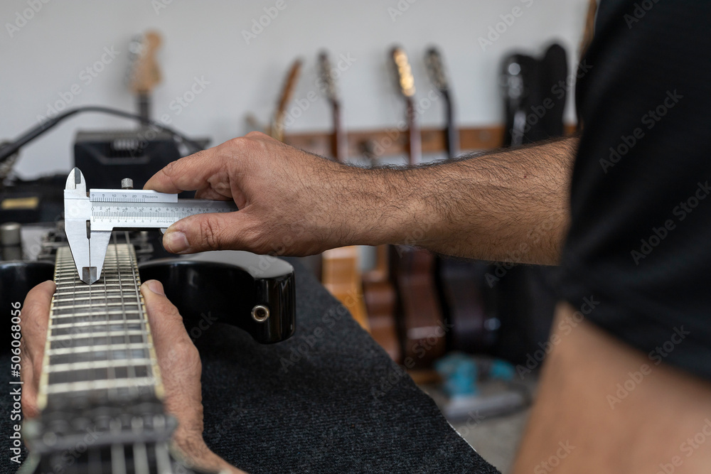 Latin American luthier accurately calibrates the strings of an electric ...