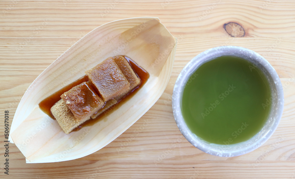 Delectable Japanese Traditional Confection Called Warabimochi in Kuromitsu Syrup with a Cup of Hot Matcha Green Tea Delectable Japanese Traditional Confection Called Warabimochi in Kuromitsu Syrup with a Cup of Hot Matcha Green Tea