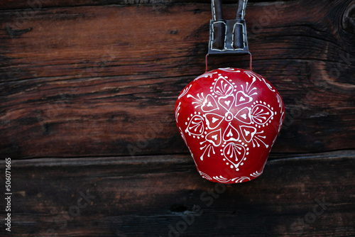 Traditional swiss cow bell red and white, decorative souvenir, on wooden background