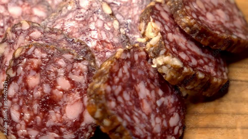Pieces of smoked sausage on a rotating wooden surface, close-up video. Soft focus, 4k. Pieces of smoked sausage on a rotating wooden surface, close-up video. Soft focus, 4k.