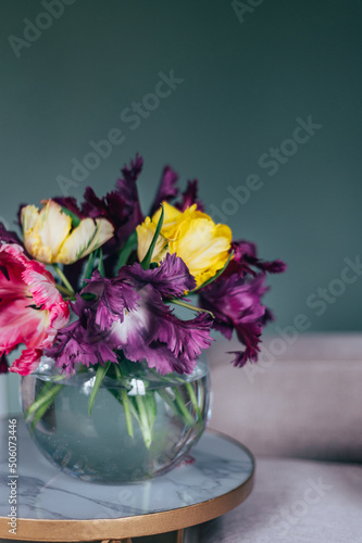 Beautiful Bunch of Parrot Style Tulips in Glass Fishbowl Vase at the coffee table in the living room on dark background  spring holiday concept  decorate your house with flowers