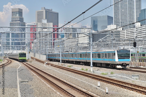 ビルを背景に走る電車（山手線と京浜東北線＠高輪ゲートウェイ駅付近2022）　Railway in Tokyo with the building in the background