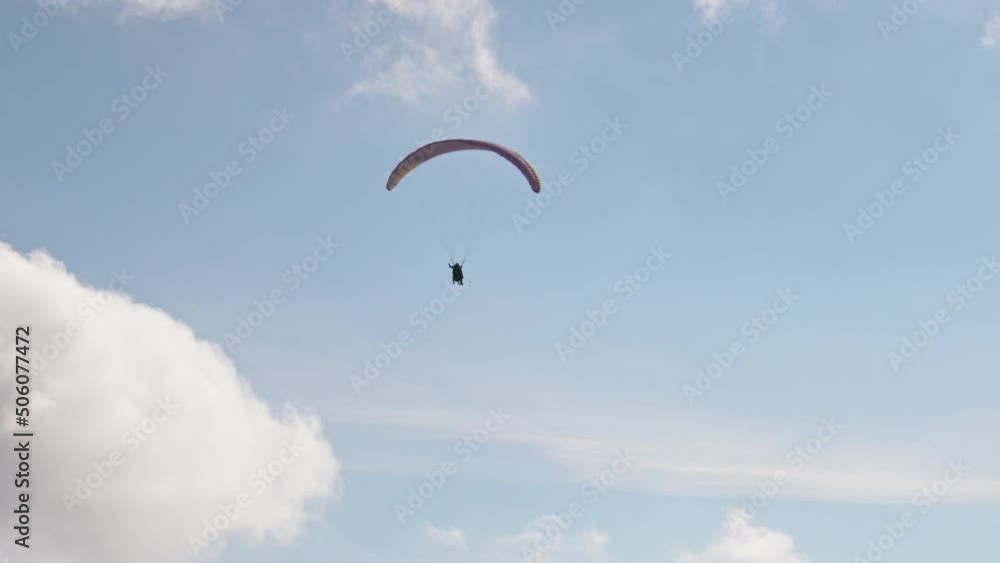 People try paragliding flying with parachutes against clouds People try paragliding flying with parachutes against clouds