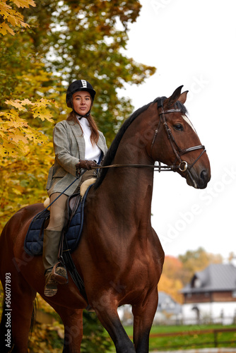 Portrait of a pretty young woman with a brown horse riding autumn day © Georgii
