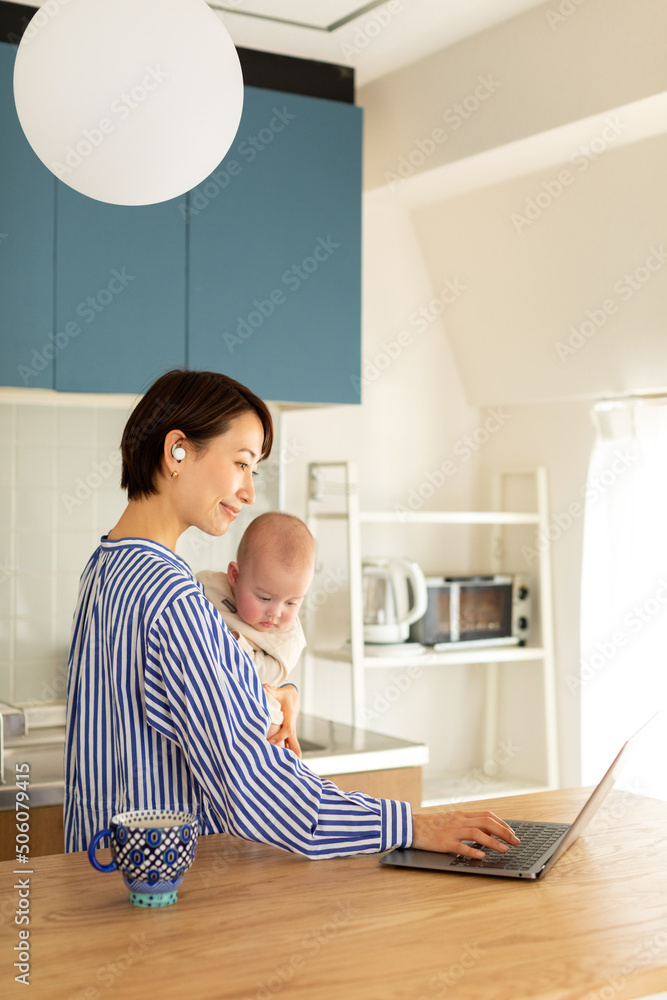赤ちゃんをあやしながら仕事をする母親 赤ちゃんをあやしながら仕事をする母親