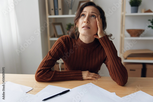 Εκτύπωση καμβά Crying upset unhappy frustrated awesome curly woman touches head with hand think about bad awful negative news sitting in home office at table