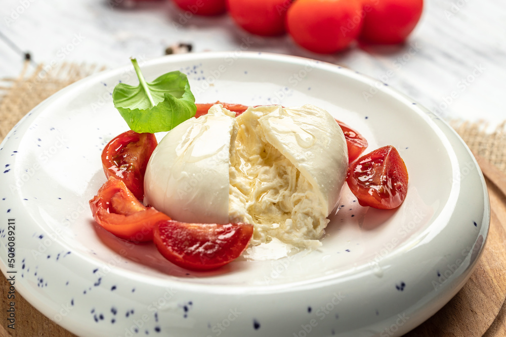 fresh soft white burrata cheese ball made from mozzarella and cream from Apulia, Italian Mediterranean cuisine, Food recipe background. Close up fresh soft white burrata cheese ball made from mozzarella and cream from Apulia, Italian Mediterranean cuisine, Food recipe background. Close up
