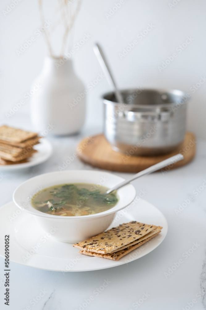 Table setting at home. Eating soup at dinner. Fresh vegetable soup with chicken broth. Healthy food concept. Minimalism in the kitchen in the interior. Table setting at home. Eating soup at dinner. Fresh vegetable soup with chicken broth. Healthy food concept. Minimalism in the kitchen in the interior.