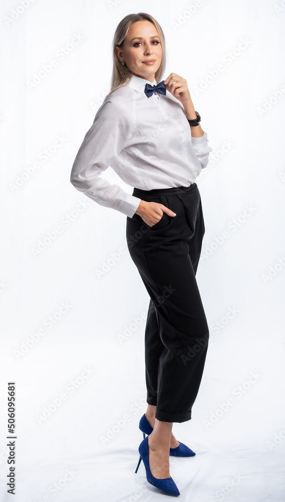 beautiful woman portrait in studio posing. a girl in a white shirt, bow tie, black trousers and stiletto heels smiles. white, isolated background beautiful woman portrait in studio posing. a girl in a white shirt, bow tie, black trousers and stiletto heels smiles. white, isolated background