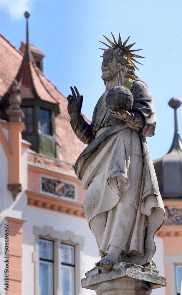 Statue des Fischerbrunnens mit dem Rathaus von Braunau am Inn im Hintergrund