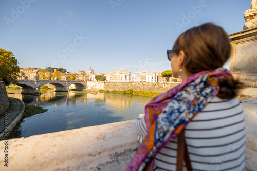 Woman enjoying beautiful view of Rome city and Vatican standing on the bridge on a sunny autumn day. Elegant woman wearing stripped blouse and shawl in hair. Concept of italian lifestyle and travel © rh2010