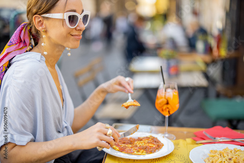 Woman eating italian pasta and drinking wine at restaurant on the street in Rome. Concept of Italian gastronomy and travel. Stylish woman with sunglasses and colorful hair shawl