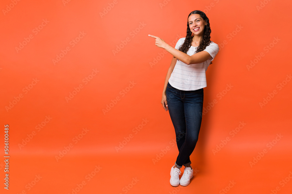 Young woman smiling and pointing to copyspace Young woman smiling and pointing to copyspace