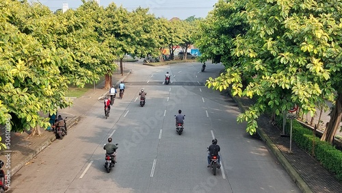 This is a situation of a street in Bintaro area, South Tangerang in Indonesia around 9am in the morning whereby  motorcycles bikers were passing by. photo