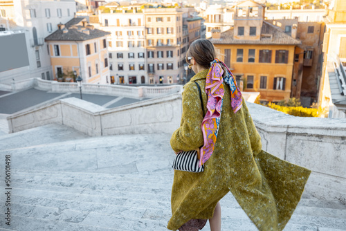 Woman running on famous Spanish steps on background of old town in Rome. Woman wearing old fashioned clothes in italian style. Concept of italian lifestyle and visiting famous italian landmarks
