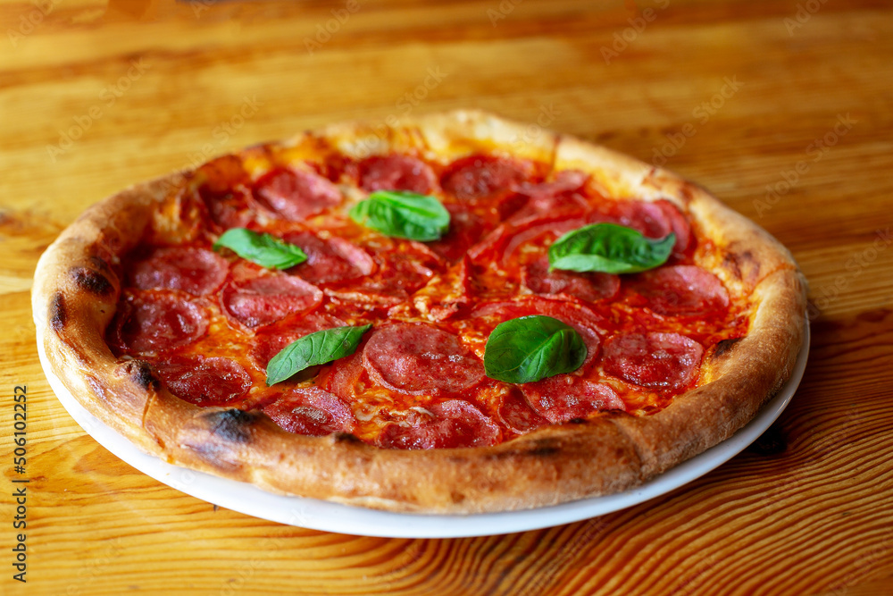Delicious salami pizza with basil and spices on table Delicious salami pizza with basil and spices on table