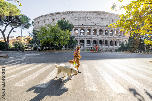 Canvas Print Woman crossing street with her dog in front of Coliseum in Rome