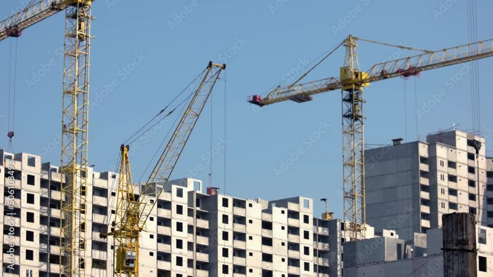 Yellow construction cranes and buildings over blue sky background. High-rise skyscrappers under construction. Yellow construction cranes and buildings over blue sky background. High-rise skyscrappers under construction.