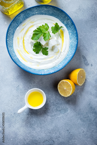 Plate with tirokafteri or greek feta dip sauce on a light-blue stone background, vertical shot with space, top view photo