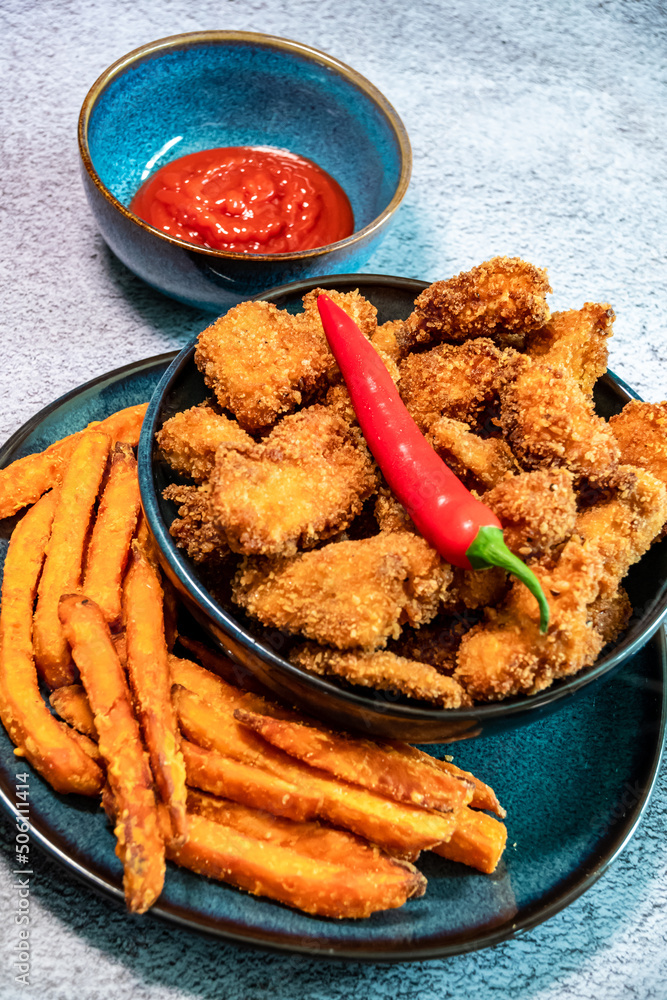 Fried, spicy chicken nuggets served with sweet potato fries. Decorated with chilli peppers - obrazy, fototapety, plakaty 
