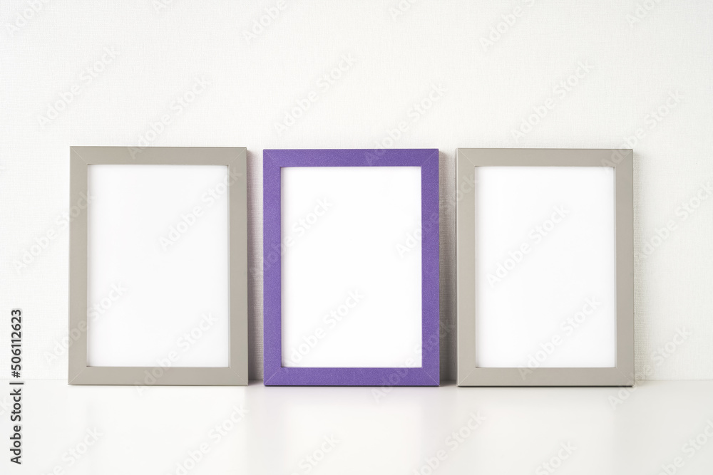 Three picture frames are placed on the white table by the wall. Copy space for text