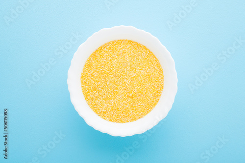 Εκτύπωση καμβά White bowl with dry yellow cornmeal porridge on light blue table background