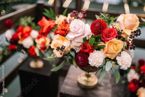 Beautiful flower composition with autumn orange and red flowers and berries. Autumn bouquet in vintage vase on a wooden table 