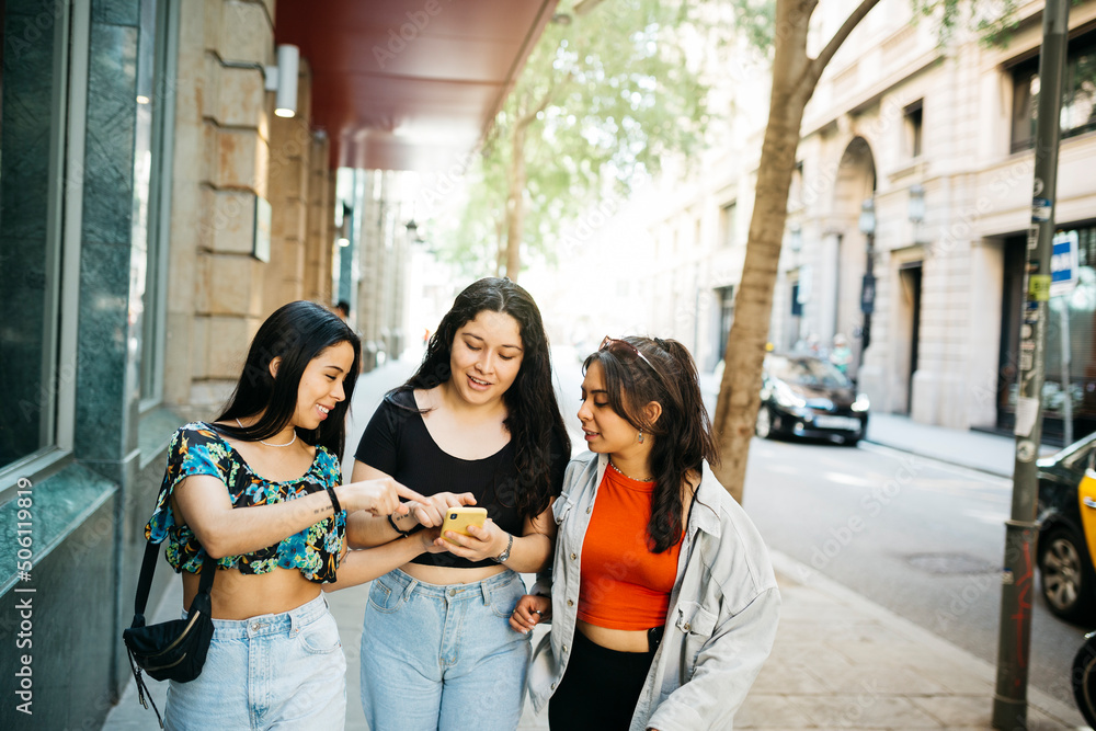 Three young women walking and hanging out on a comercial street of a big city Three young women walking and hanging out on a comercial street of a big city