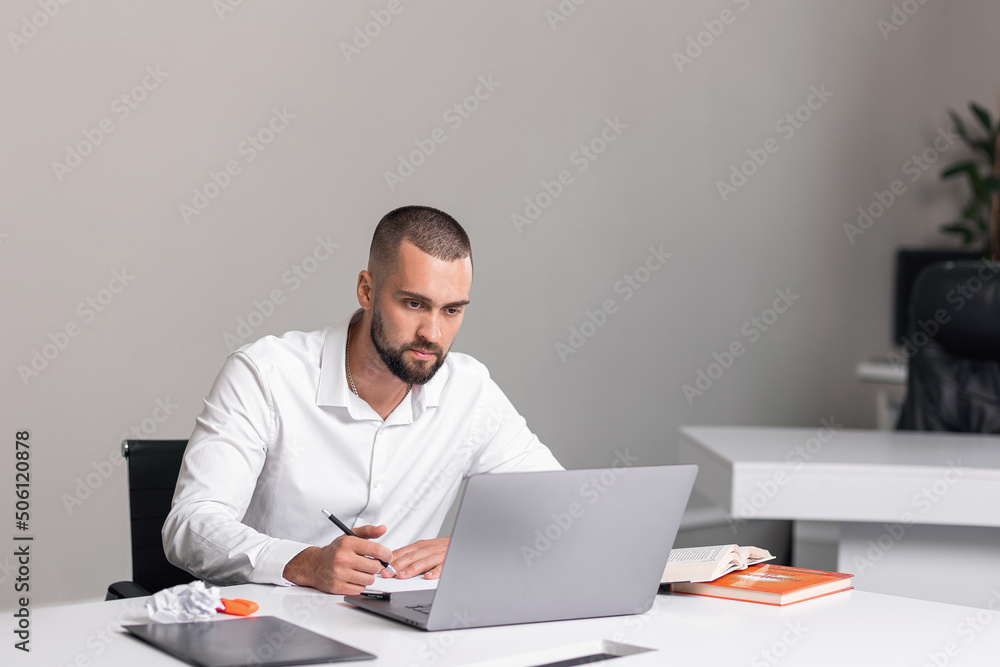 handsome man in bright office behind laptop handsome man in bright office behind laptop