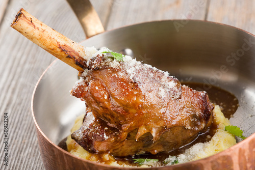Juicy roasted duck leg with mashed potatoes in a serving frying pan.