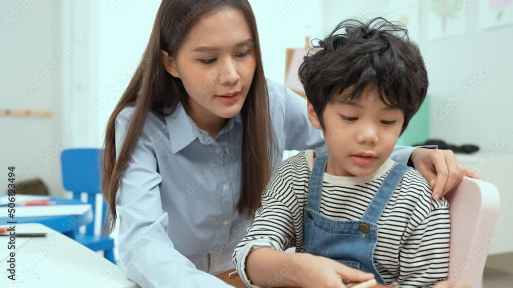 Young asian teacher teaching guitar and ukulele to his little boy.Little boy learning guitar at kindergarten.Close up,Ukulele class at school. Child learning guitar from her teacher.Musical education. Young asian teacher teaching guitar and ukulele to his little boy.Little boy learning guitar at kindergarten.Close up,Ukulele class at school. Child learning guitar from her teacher.Musical education.