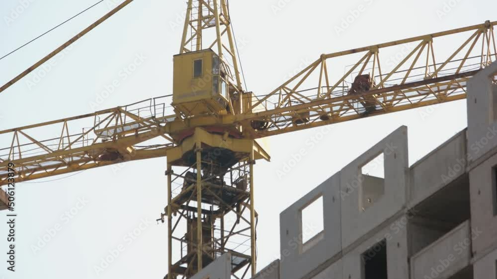Yellow crane on the construction moving to the right. White sky background. Yellow crane on the construction moving to the right. White sky background.