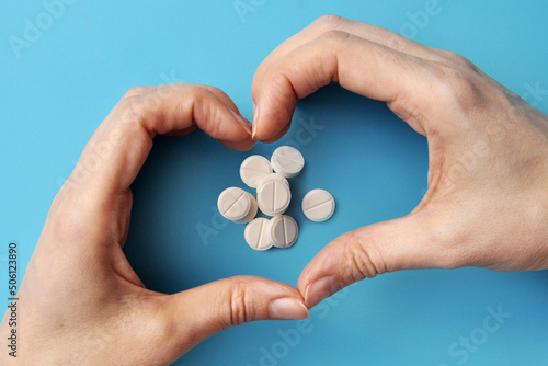 Hands in the form of a heart and pills inside. A symbol of the treatment of heart diseases