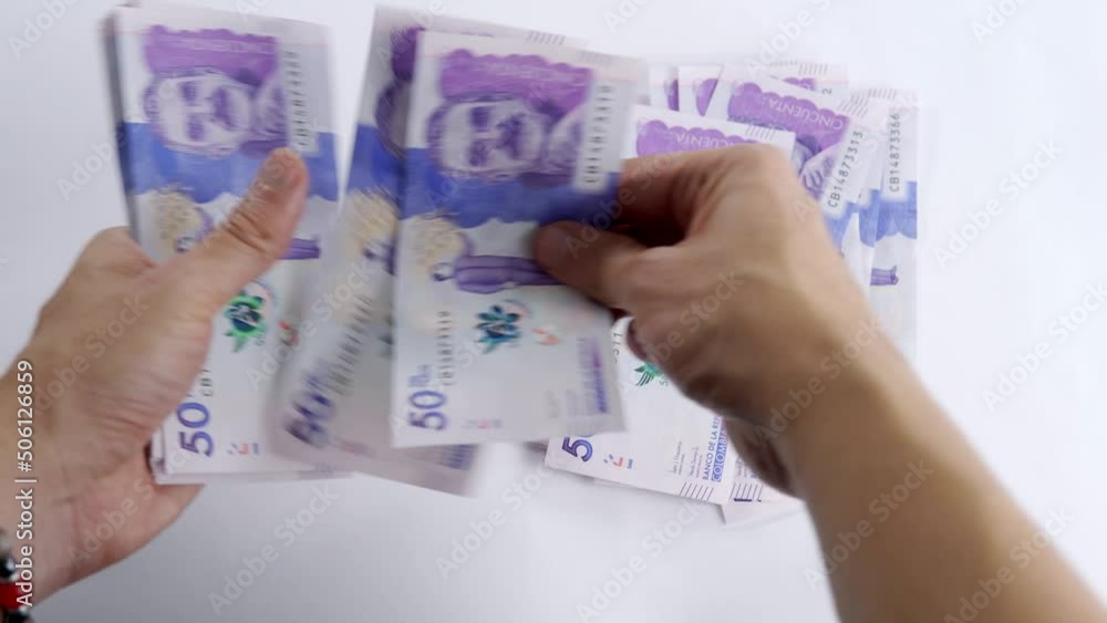 hands counting Colombian money on a white background hands counting Colombian money on a white background