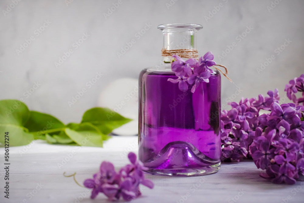 Lilac extract in a glass bottle on a light background Lilac extract in a glass bottle on a light background