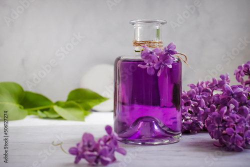 Lilac extract in a glass bottle on a light background
