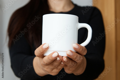 White mug for tea and coffee in the hands of a girl, close-up