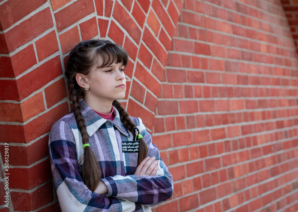 A teenage girl stands near a brick wall. Beautiful brick wall A teenage girl stands near a brick wall. Beautiful brick wall