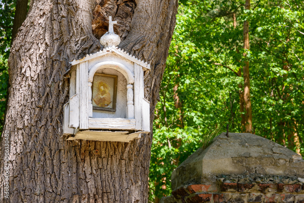 Mała drewniana kapliczka zawieszona na drzewie. - obrazy, fototapety, plakaty 
