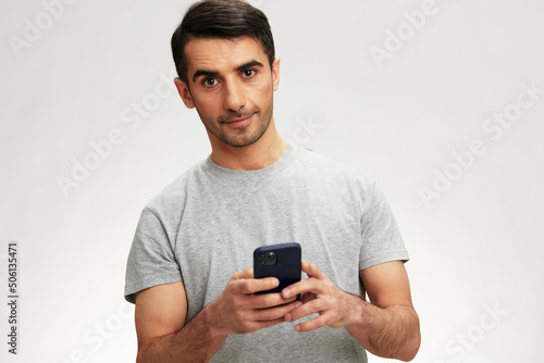 man in a gray t-shirt with a phone communication technology isolated background © SHOTPRIME STUDIO