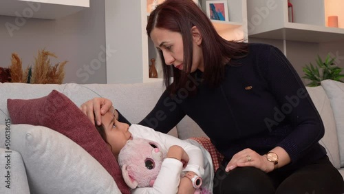 Fever little girl and her mother.
The mother takes care of the fever of her sick little daughter. He puts his hand on his forehead.

