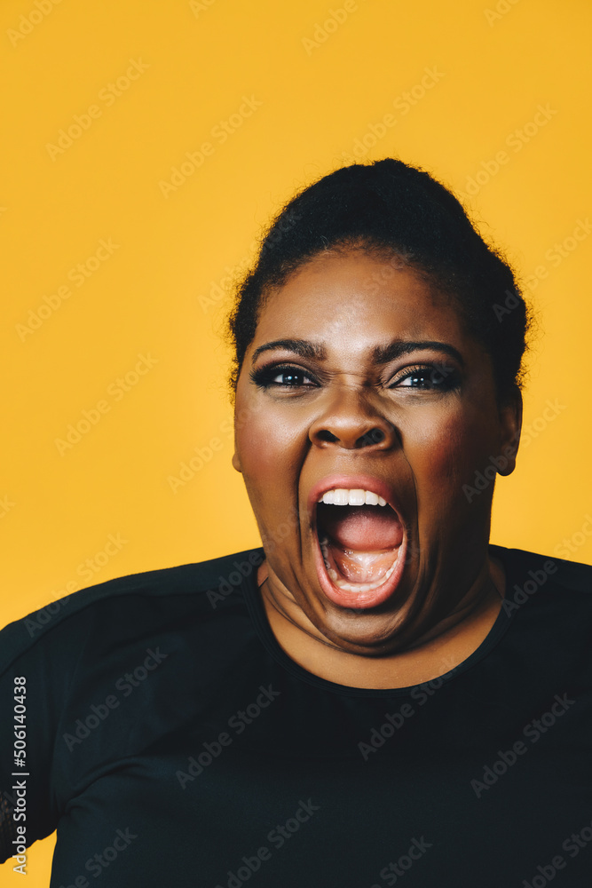 closeup portrait of a young adult african american woman in shock with mouth open screaming on yellow background studio closeup portrait of a young adult african american woman in shock with mouth open screaming on yellow background studio