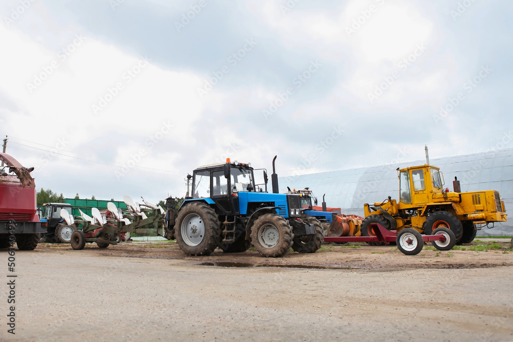 Obraz premium Agricultural machinery, tractors and equipment outdoors, near the garage, ready to work in the field.