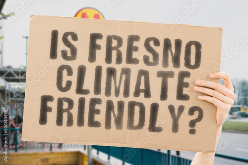 The question   Is Fresno climate-friendly    is on a banner in men s hands with blurred background. Support. Team. Activist. Urban. Sunset. Carbon. Ecology. Energy. New. Clean. Warming. Waste