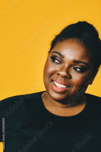 closeup portrait of a beautiful young african american woman smiling with afro hairstyle on yellow background studio © Carlos David