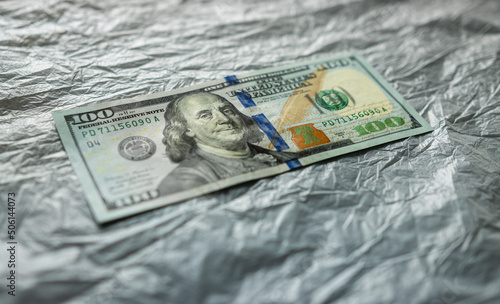 textured background of one hundred dollar bill with a portrait of us President Franklin in orange, red and black colors. blur, defocus.