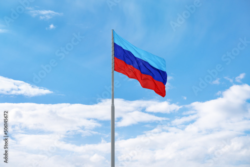 Flag of the self-proclaimed Luhansk People's Republic (LPR or LNR) is waving in front of blue sky and clouds photo